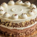 A multi-flavored layered cake with vanilla and chocolate frosting, topped with whipped cream dollops and sprinkled with chocolate and nut toppings.